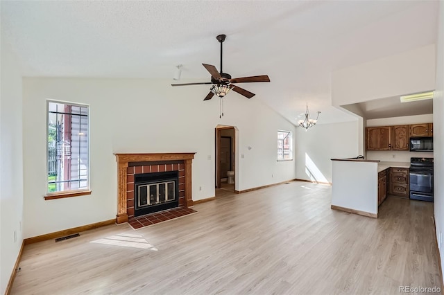 unfurnished living room featuring a fireplace, vaulted ceiling, light wood-type flooring, and ceiling fan with notable chandelier