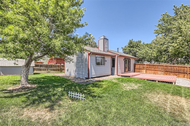 rear view of property featuring a yard, a storage unit, and a deck