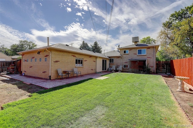 back of property with central AC unit, a patio area, and a yard