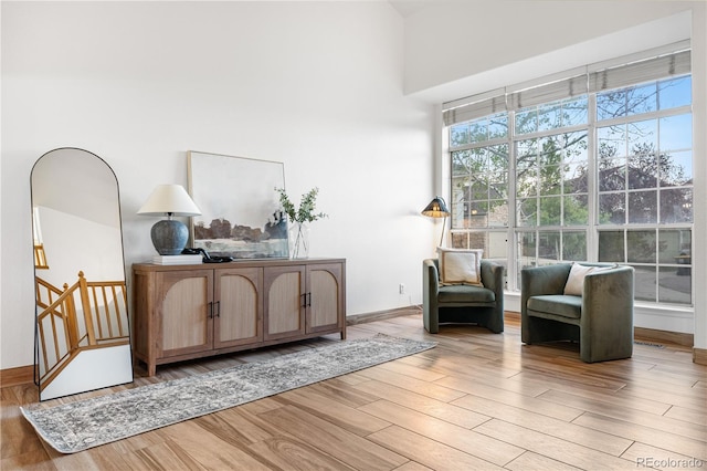 sitting room featuring light wood-style flooring and a high ceiling