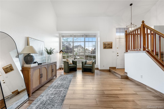 sitting room with light wood-style floors, a chandelier, baseboards, and stairway