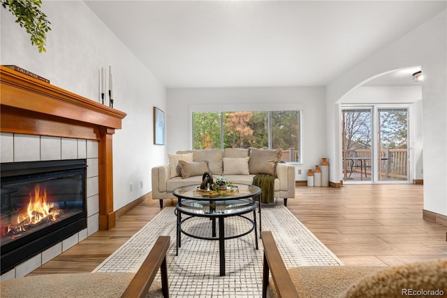 living area with wood finished floors, a fireplace, baseboards, and arched walkways