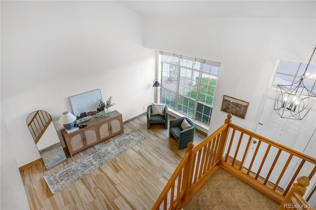 living area featuring a chandelier, wood finished floors, a high ceiling, stairway, and baseboards