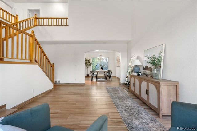 foyer featuring a chandelier, arched walkways, light wood finished floors, stairway, and a high ceiling