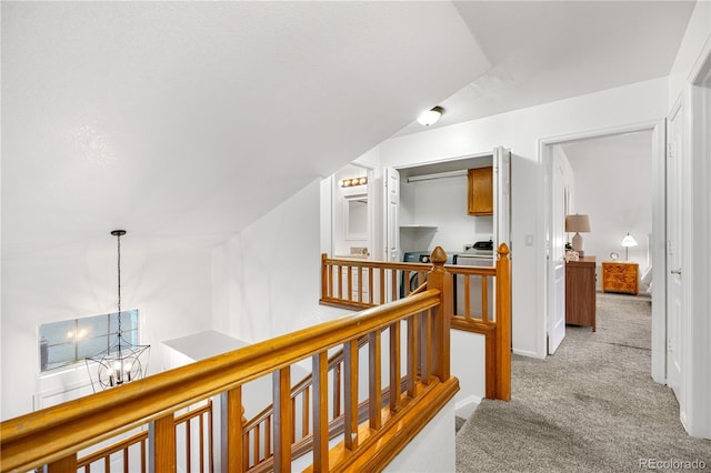 hallway featuring carpet flooring, an upstairs landing, and a chandelier