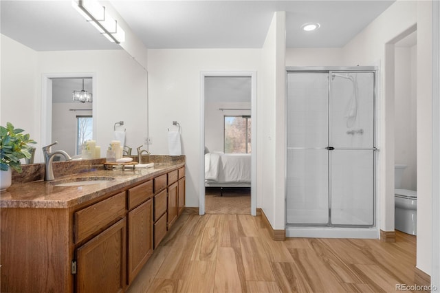 ensuite bathroom with healthy amount of natural light, a shower stall, wood finished floors, and double vanity