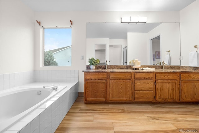 full bathroom with a garden tub, double vanity, wood finished floors, and a shower with door