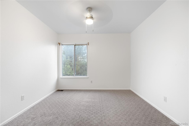 carpeted spare room featuring ceiling fan and baseboards