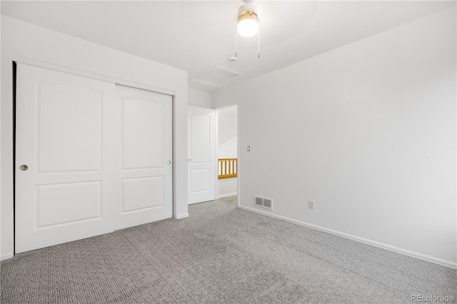 unfurnished bedroom featuring carpet flooring, a closet, baseboards, attic access, and ceiling fan