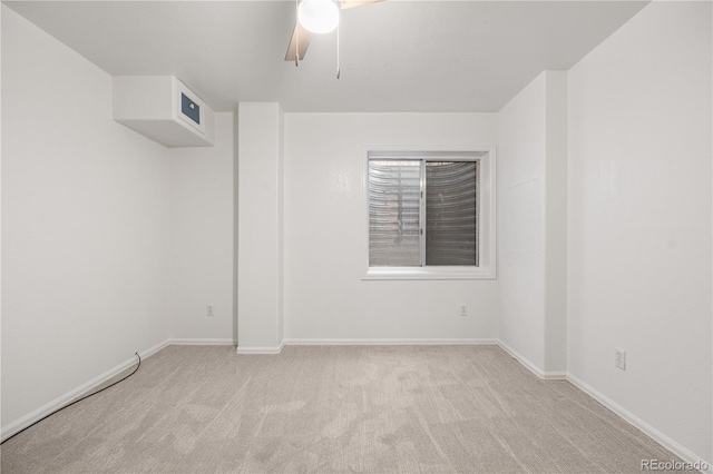 spare room featuring light carpet, a ceiling fan, and baseboards