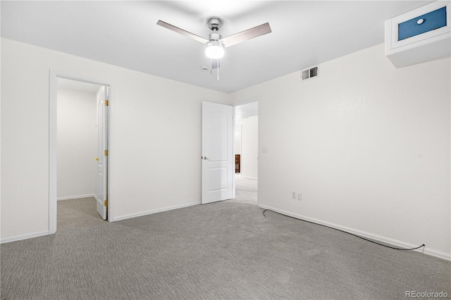 unfurnished bedroom with carpet, a walk in closet, baseboards, and a ceiling fan