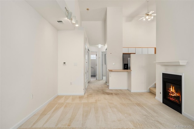 unfurnished living room featuring ceiling fan and light carpet