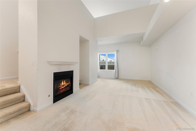 unfurnished living room featuring light carpet and high vaulted ceiling