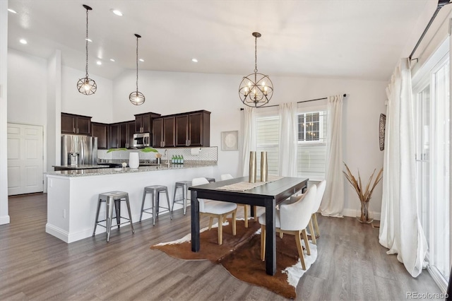 dining room featuring a chandelier, high vaulted ceiling, and wood-type flooring