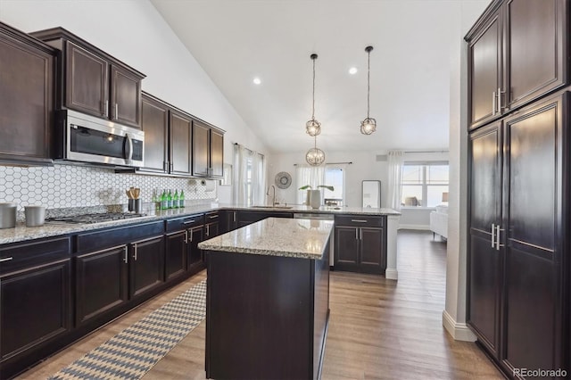 kitchen with a center island, hanging light fixtures, vaulted ceiling, kitchen peninsula, and stainless steel appliances