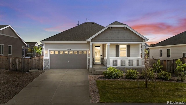 view of front of home featuring covered porch, a garage, and a lawn