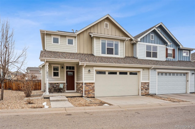 view of front of house featuring a shingled roof, board and batten siding, a garage, stone siding, and driveway