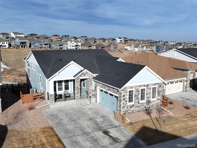 view of front facade with concrete driveway, a residential view, a garage, and stone siding