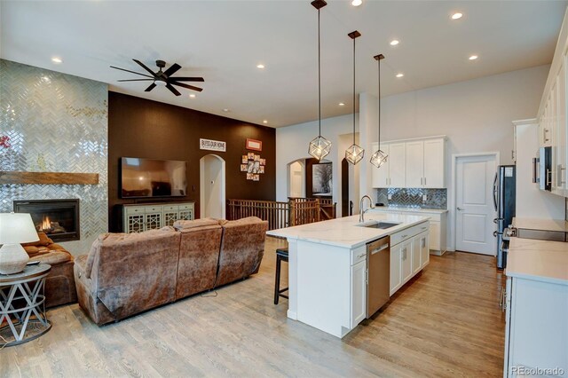 kitchen featuring open floor plan, arched walkways, appliances with stainless steel finishes, and a sink