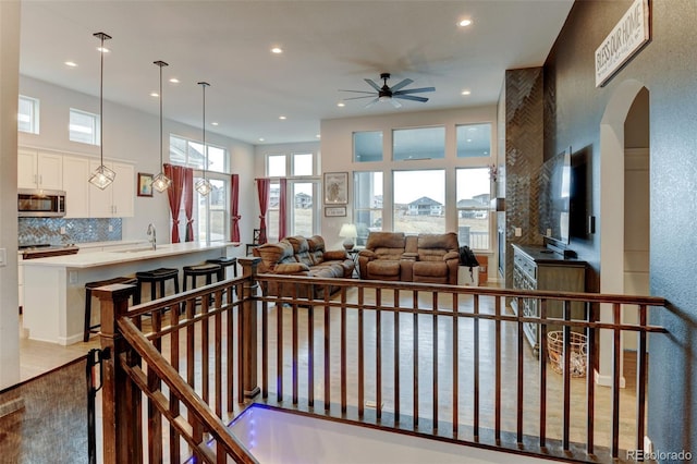 living area with a ceiling fan, arched walkways, and recessed lighting