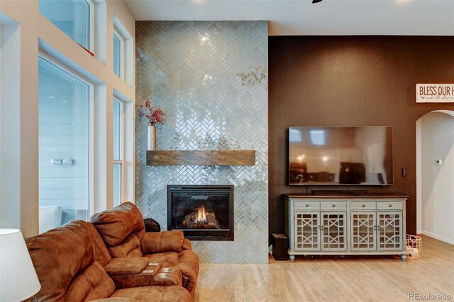 living area with arched walkways, wood finished floors, and a fireplace