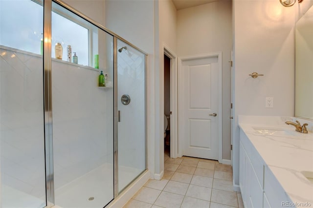 full bath featuring a shower stall, tile patterned floors, vanity, and baseboards