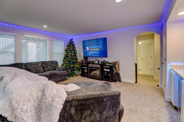 carpeted living room with baseboards, recessed lighting, arched walkways, and a fireplace