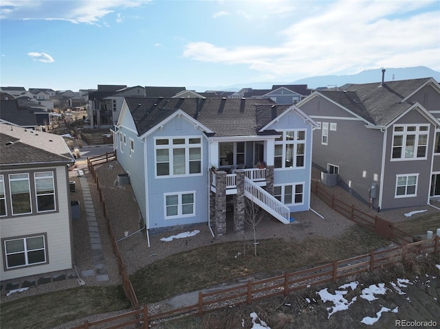 rear view of house featuring a mountain view, a fenced backyard, central air condition unit, stairs, and a residential view