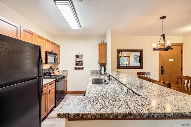 22787 US Highway 6 Unit 313, Dillon, CO 80435 - kitchen featuring black appliances, a sink, a peninsula, stone counters, and a chandelier