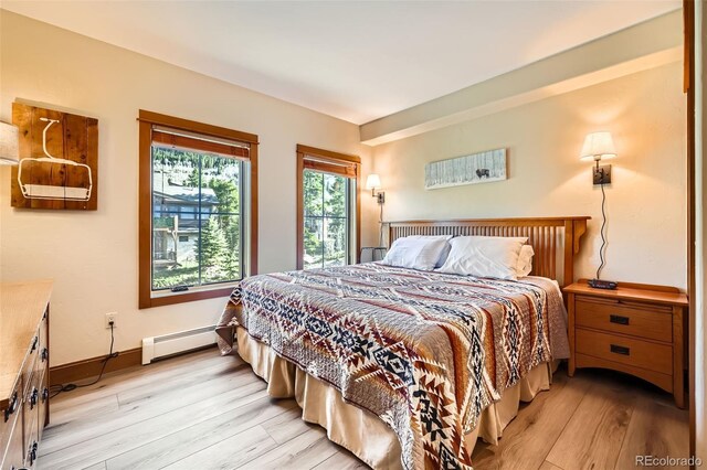 22787 US Highway 6 Unit 313, Dillon, CO 80435 - bedroom featuring a baseboard heating unit, light wood-style flooring, and baseboards