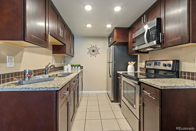 kitchen featuring a sink, recessed lighting, appliances with stainless steel finishes, light tile patterned flooring, and baseboards