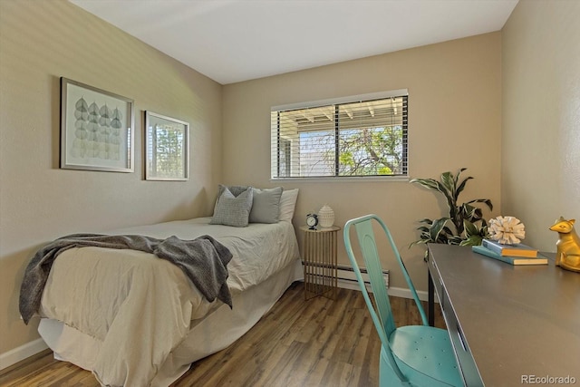 bedroom with a baseboard heating unit, baseboards, and wood finished floors