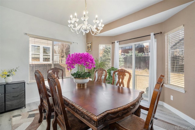 dining space with baseboards, an inviting chandelier, and light wood finished floors