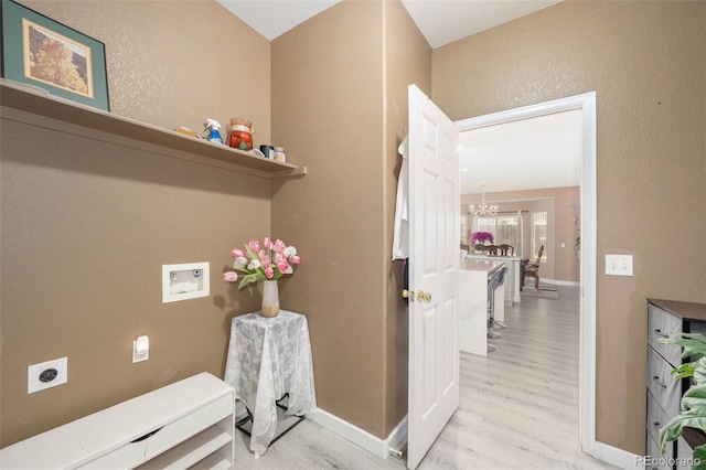 clothes washing area featuring light wood finished floors, laundry area, hookup for a washing machine, an inviting chandelier, and hookup for an electric dryer