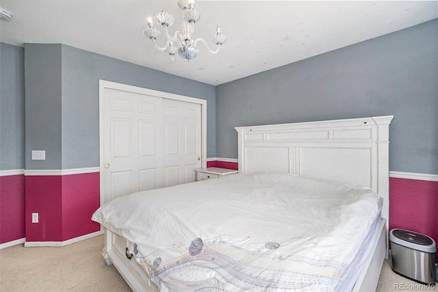 bedroom with an inviting chandelier, baseboards, a closet, and light carpet