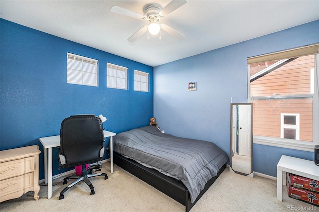 carpeted bedroom with a textured wall, baseboards, and ceiling fan