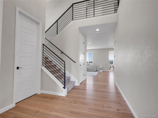 foyer featuring recessed lighting, baseboards, light wood finished floors, and stairs
