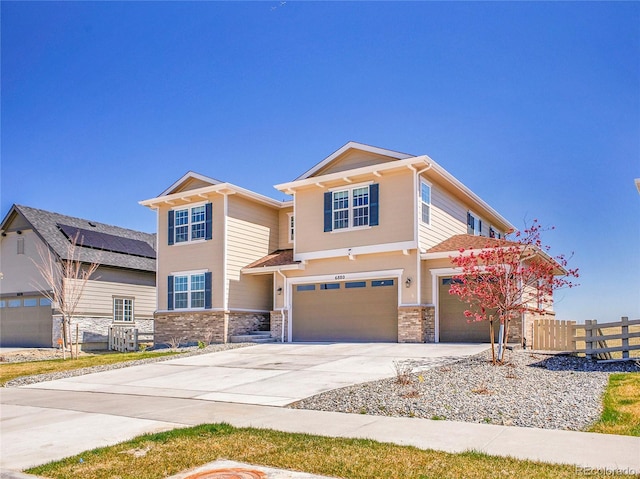 craftsman inspired home with a garage, fence, driveway, and stone siding