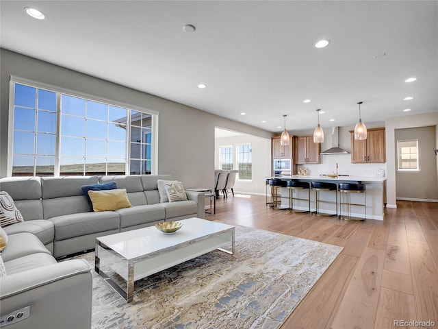 living room featuring recessed lighting, baseboards, and light wood-style floors