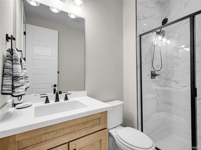 full bathroom with a marble finish shower, a textured wall, vanity, and toilet