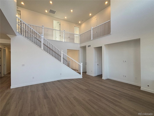 unfurnished living room featuring dark hardwood / wood-style flooring and a towering ceiling