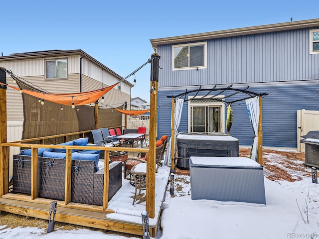 snow covered back of property featuring a hot tub, a deck, a pergola, and an outdoor hangout area