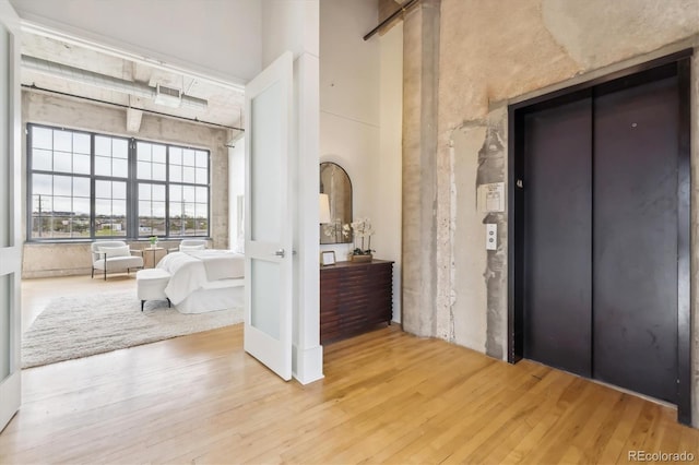 interior space featuring elevator, wood finished floors, and a towering ceiling