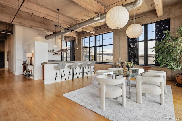 dining space featuring visible vents, hardwood / wood-style floors, and a towering ceiling