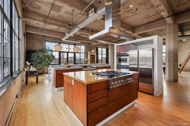 kitchen with island exhaust hood, visible vents, a center island, stainless steel appliances, and light wood-style flooring