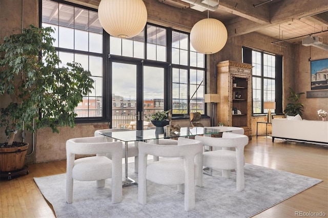 dining space with wood ceiling, beamed ceiling, wood finished floors, and a towering ceiling