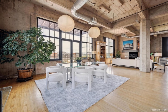 dining space featuring wood ceiling, visible vents, a towering ceiling, a fireplace, and hardwood / wood-style flooring
