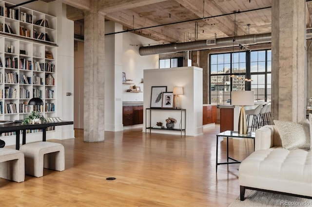 living area with baseboards, a high ceiling, and wood finished floors
