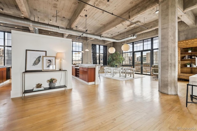 interior space featuring a high ceiling, visible vents, a wealth of natural light, and light wood finished floors