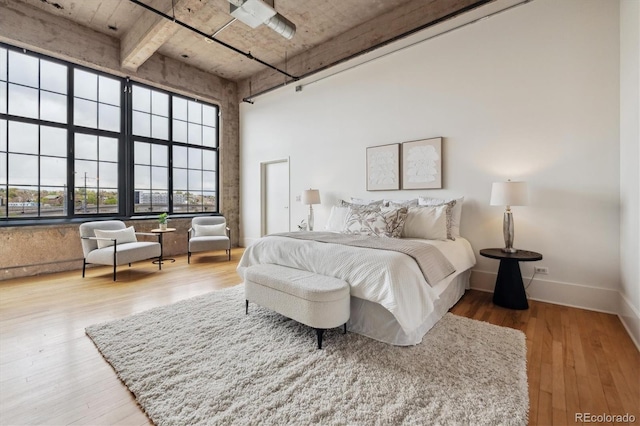 bedroom featuring baseboards, a high ceiling, and wood finished floors